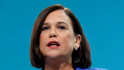 Reuters Sinn Fein President Mary Lou McDo<em></em>nald delivers a speech at the Sinn Fein annual party co<em></em>nference in Athlone. She has shoulder length brown hair and brown eyes.