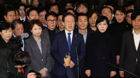 Reuters The leader of a key opposition party, the Democrats Party, stands with several other lawmakers while addressing media after parliament voted down martial law on Wednesday morning